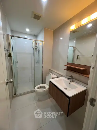 Modern bathroom with glass shower and sleek vanity in contemporary apartment.