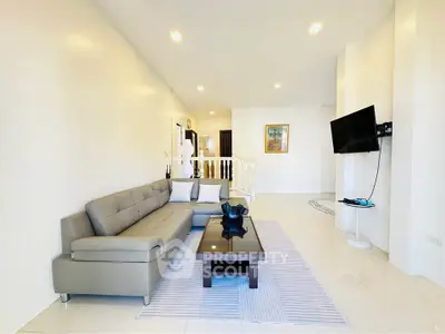 Spacious modern living room with sleek furniture and wall-mounted TV