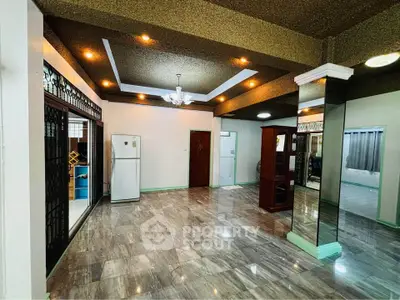 Spacious living room with modern lighting and open layout, featuring a fridge and elegant flooring.