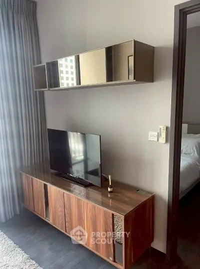 Modern living room with sleek wooden TV cabinet and wall-mounted storage in a stylish apartment.