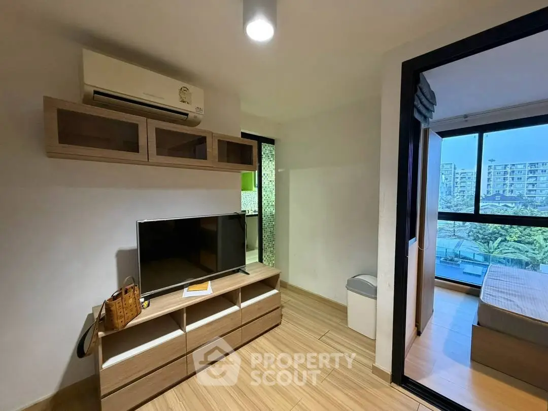 Modern apartment interior with TV unit and air conditioning, featuring a glimpse into a cozy bedroom with city view.
