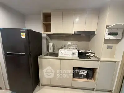 Modern kitchen with sleek cabinetry and appliances, featuring a fridge and microwave in a compact layout.