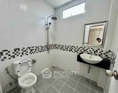 Modern bathroom with sleek design, featuring a shower, toilet, and stylish sink in a tiled setting.