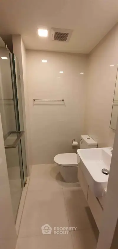 Modern minimalist bathroom with sleek fixtures and glass shower enclosure.