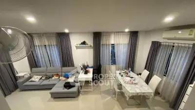 Spacious living room with modern decor and dining area, featuring a cozy sofa and elegant curtains.