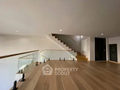 Spacious modern interior with wooden flooring and sleek staircase, perfect for contemporary living.