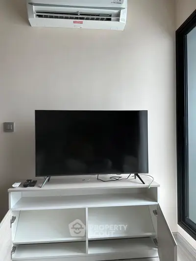 Modern living room with sleek TV setup and air conditioning unit.