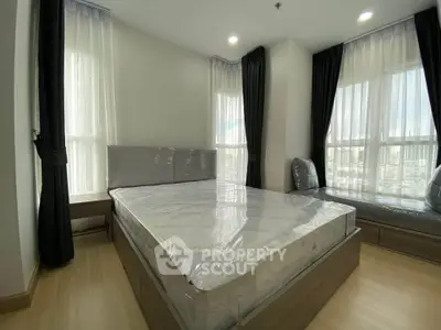 Spacious bedroom with large windows and modern furnishings in a high-rise apartment.