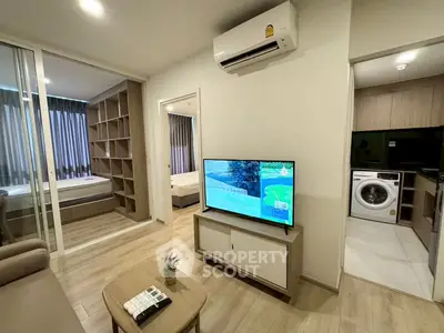 Modern living room with TV, air conditioning, and view into bedroom and laundry area.