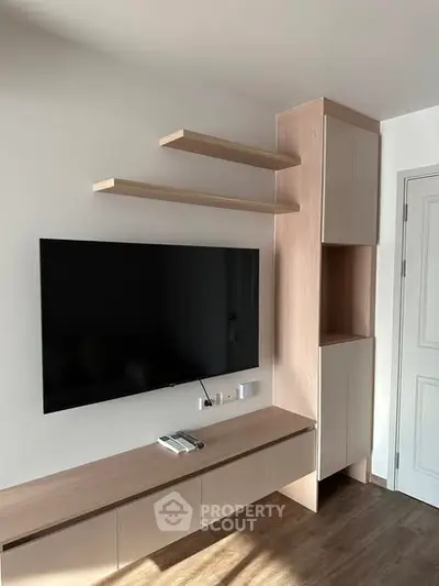 Modern living room with sleek TV setup and stylish wooden cabinetry.