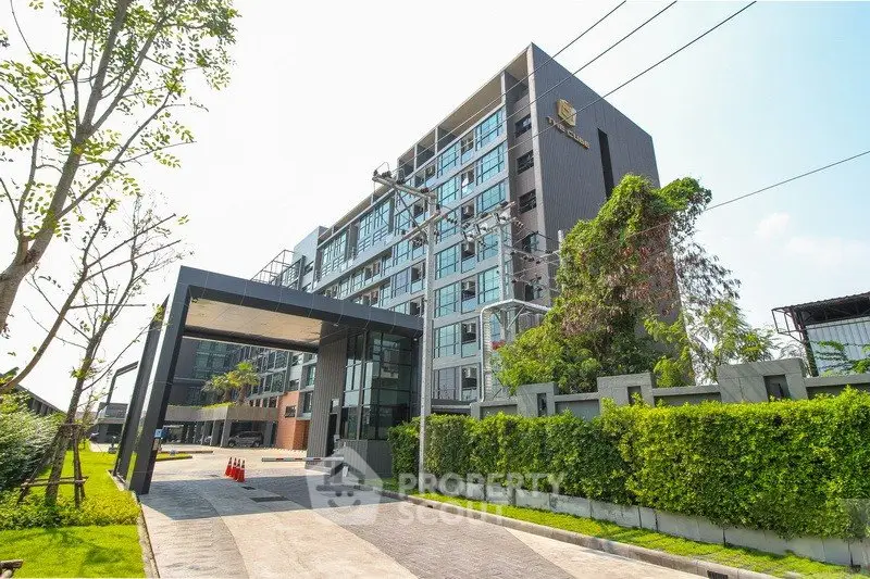Modern apartment building with lush greenery and sleek entrance.