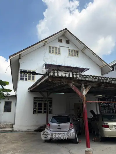 Charming two-story house with carport under a clear blue sky, perfect for family living.