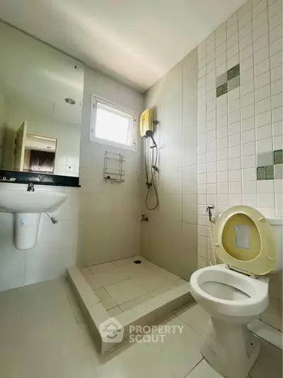 Modern bathroom with shower, toilet, and sink in a minimalist design.