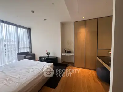 Spacious bedroom with modern decor and large window offering city views.