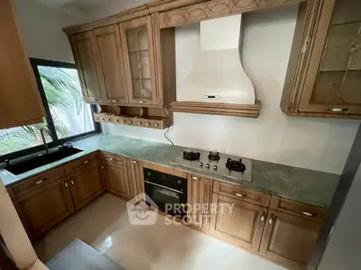 Elegant kitchen with wooden cabinetry, gas stove, and built-in oven, perfect for culinary enthusiasts.