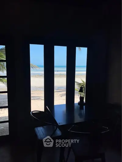 Stunning beachfront view from cozy dining area with ocean backdrop.