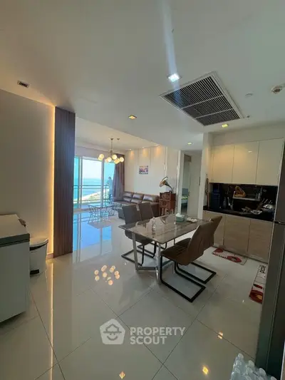 Luxurious open-plan living and dining area with stunning ocean view, modern furnishings, and elegant lighting.