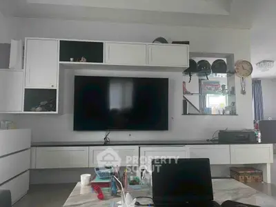 Modern living room with sleek white cabinetry and large flat-screen TV, perfect for entertainment.