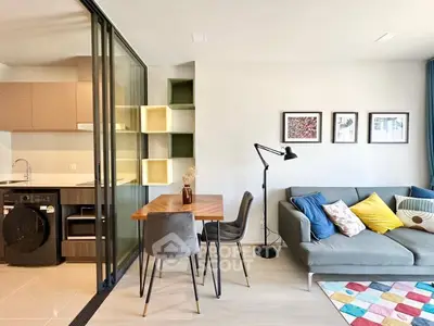 Modern living room with stylish decor and open kitchen layout, featuring a cozy sofa and vibrant rug.