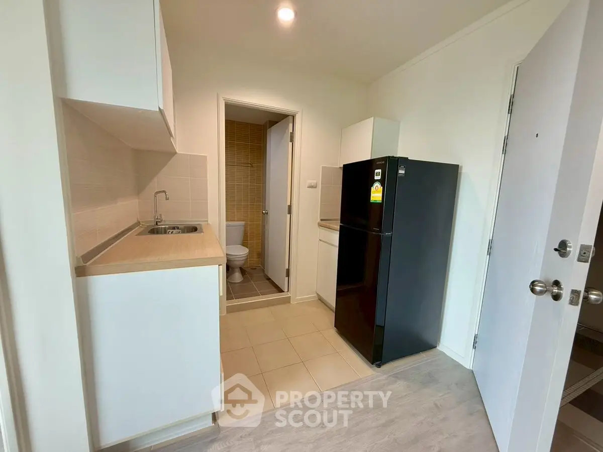 Compact kitchen with modern appliances and adjacent bathroom in a cozy apartment.