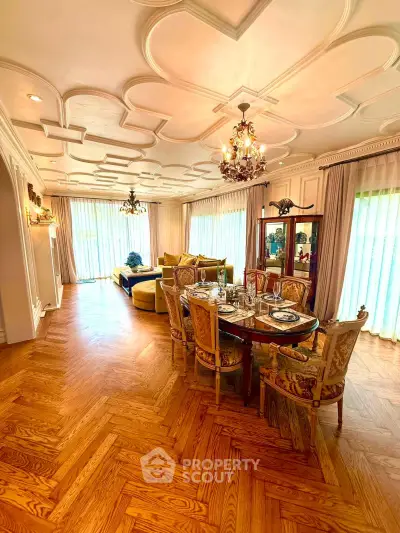 Luxurious living room with elegant dining area, ornate ceiling, and large windows for natural light.