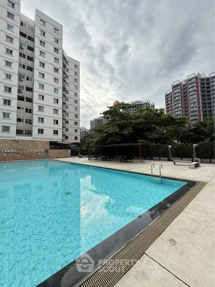 Modern residential building with a spacious outdoor pool area and lush greenery.