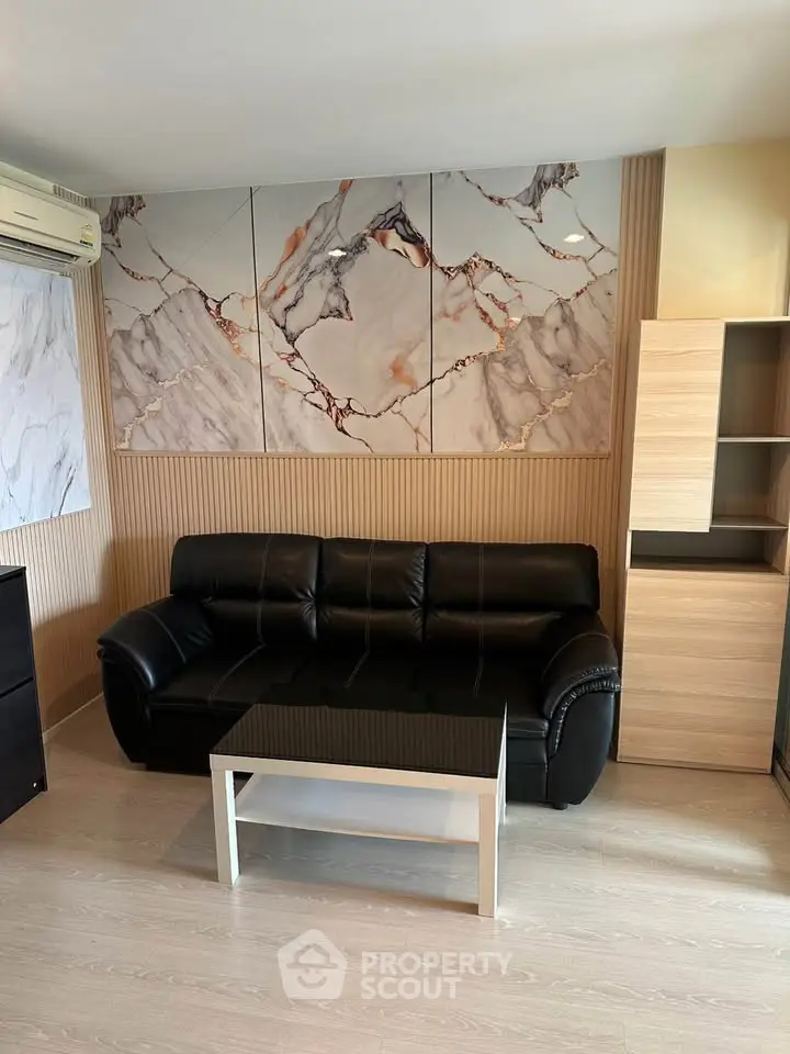 Modern living room with stylish marble wall art and black leather sofa, perfect for contemporary urban living.