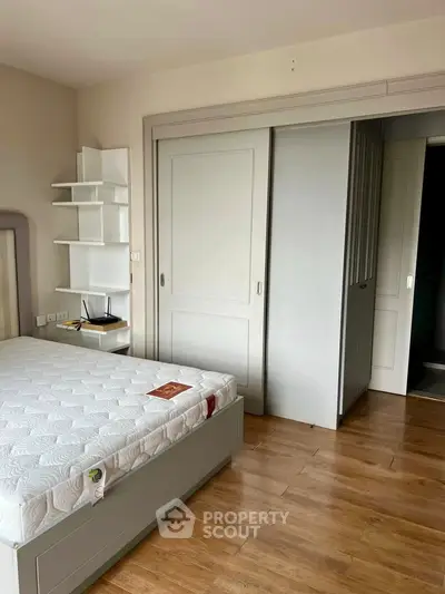 Spacious bedroom with wooden flooring and built-in closet, perfect for modern living.