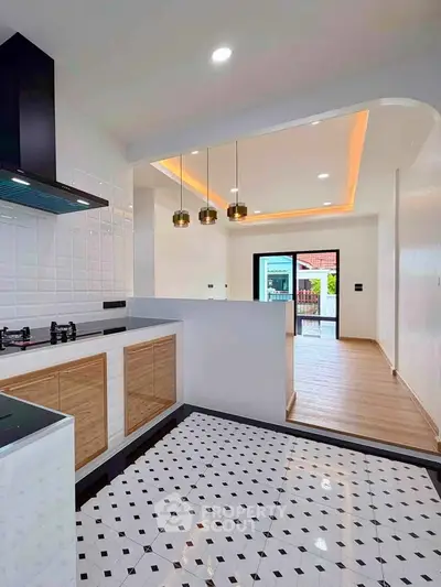 Modern kitchen with open layout and stylish lighting, featuring a gas stove and elegant tile flooring.