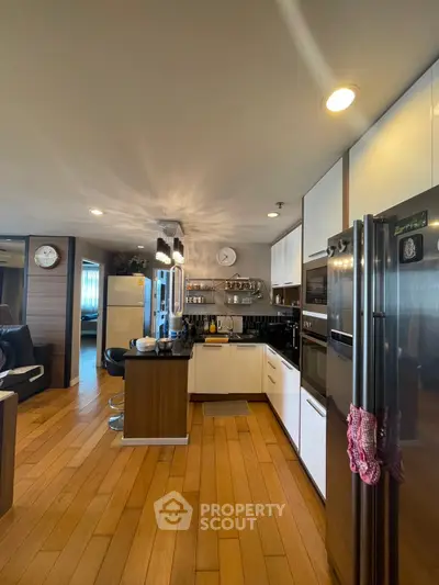 Modern kitchen with sleek appliances and wooden flooring, open layout design.