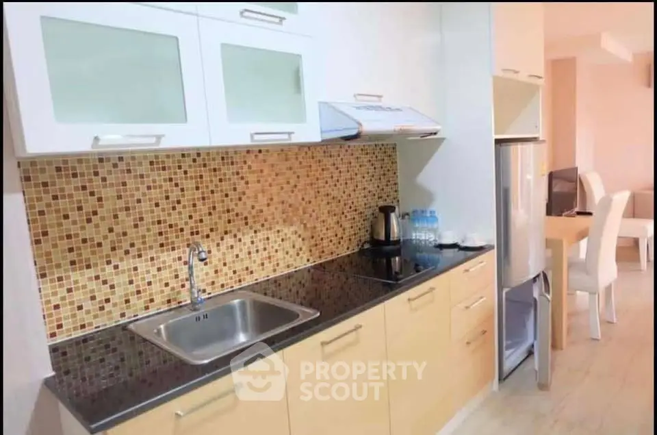 Modern kitchen with mosaic backsplash and sleek cabinetry in open layout apartment.