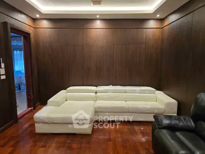 Luxurious living room with elegant wood paneling and plush white sectional sofa.