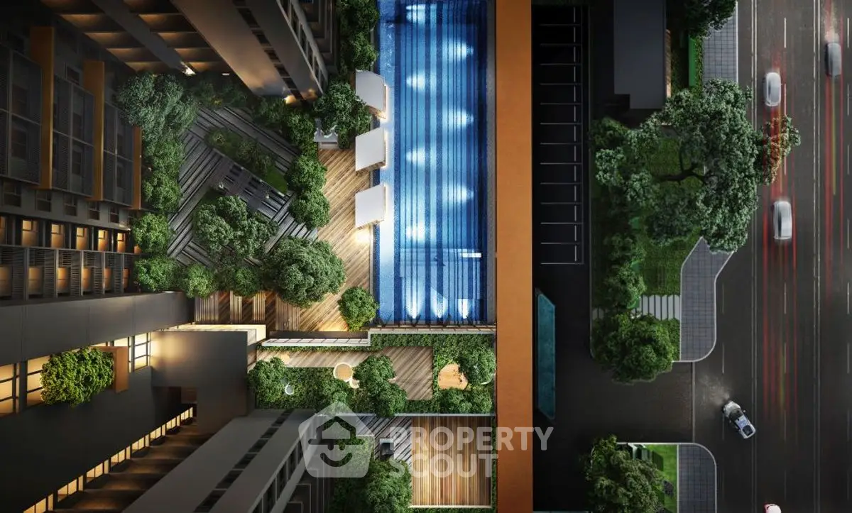 Stunning aerial view of modern apartment complex with illuminated pool and lush greenery.