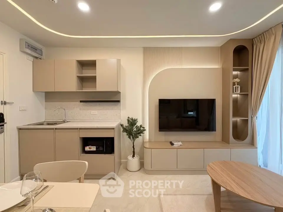 Modern living room with integrated kitchen, featuring sleek cabinetry and stylish decor.