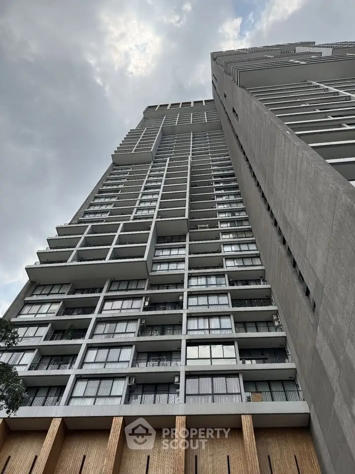 Stunning high-rise building with modern architecture and expansive balconies against a cloudy sky.