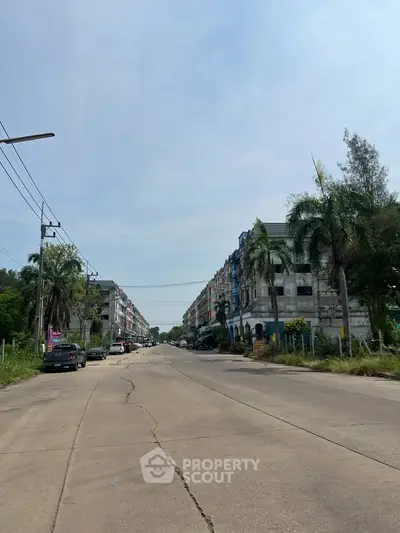 Street view of residential buildings with palm trees and clear sky