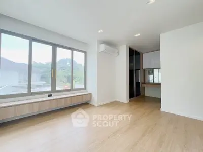 Spacious modern living room with large windows and wooden flooring.