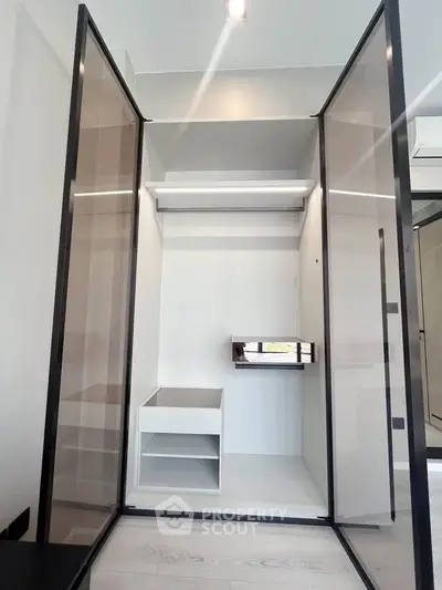 Modern walk-in closet with sleek glass doors and ample storage space