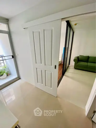 Modern apartment with sliding doors and balcony access, featuring a cozy green sofa in the living area.