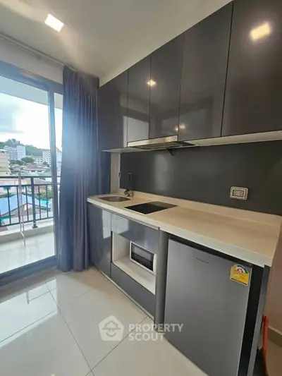 Modern kitchen with sleek cabinets and balcony view in urban apartment