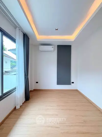 Spacious modern room with elegant lighting and large window, perfect for customization.