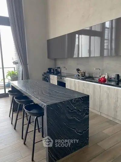 Modern kitchen with sleek marble island and high cabinets in luxury apartment