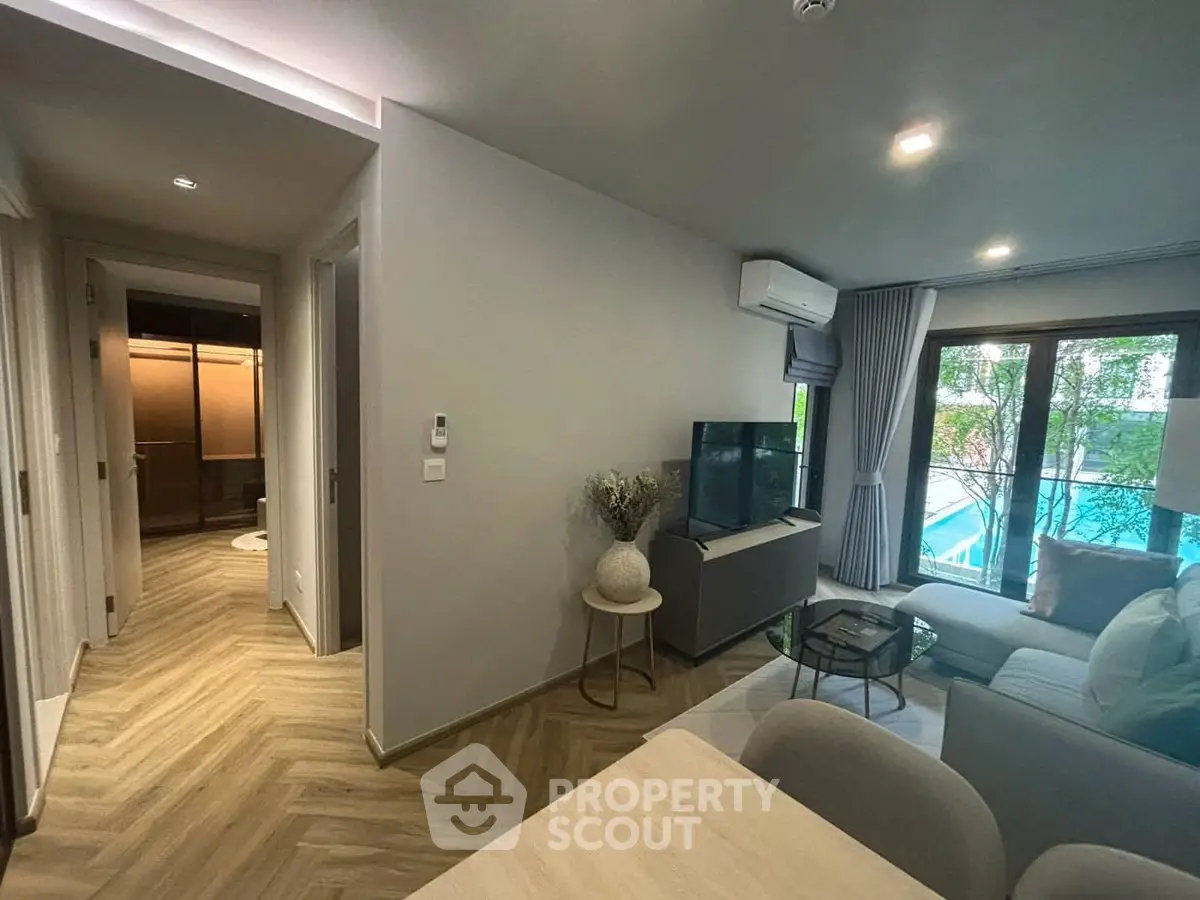 Modern living room with pool view, stylish decor, and natural light.