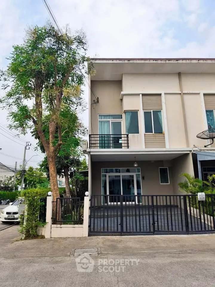 Modern two-story townhouse with gated entrance and balcony in a suburban neighborhood.
