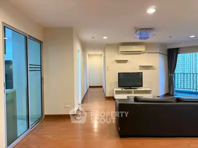 Spacious modern living room with sleek black sofa and large balcony view.