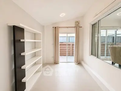 Spacious room with large window and modern shelving unit, perfect for versatile living space.