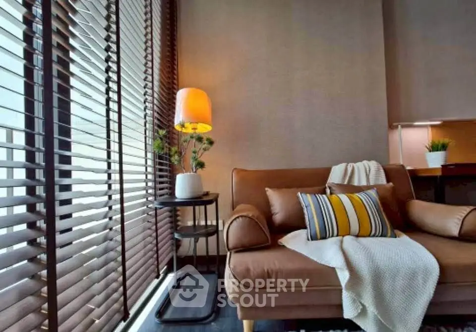 Stylish living room with cozy sofa and modern decor, featuring large windows with blinds.