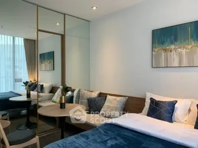 Modern bedroom with stylish decor and cozy seating area, featuring elegant artwork and natural light.