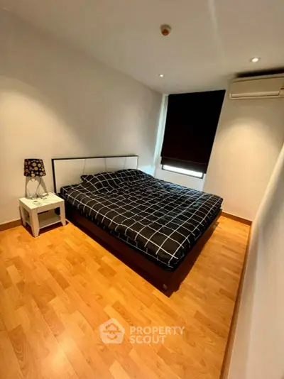 Modern bedroom with stylish decor and wooden flooring, featuring a cozy bed and ambient lighting.