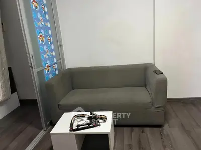 Cozy living room with gray sofa and small white table on wooden floor.